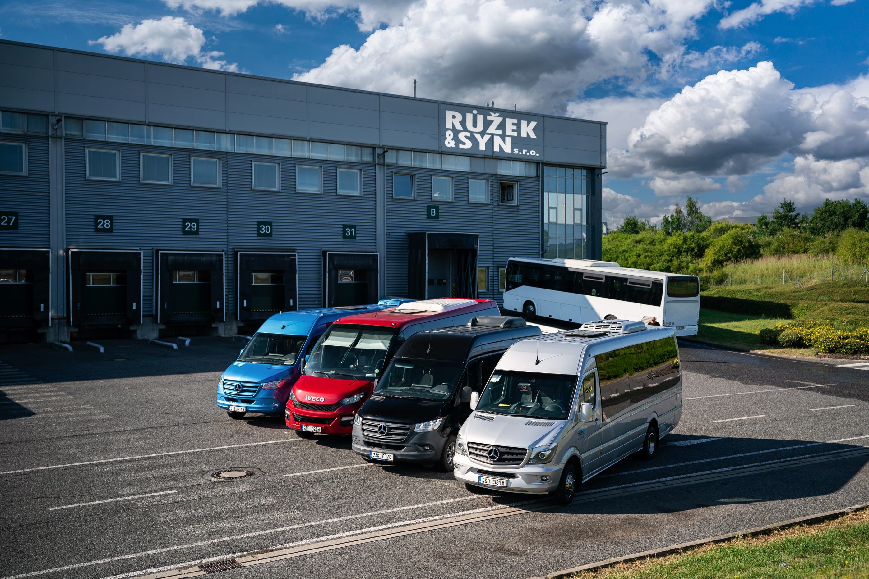 Různé druhy aut včetně autobusů, minibusů a dodávek připravených na výjezd.